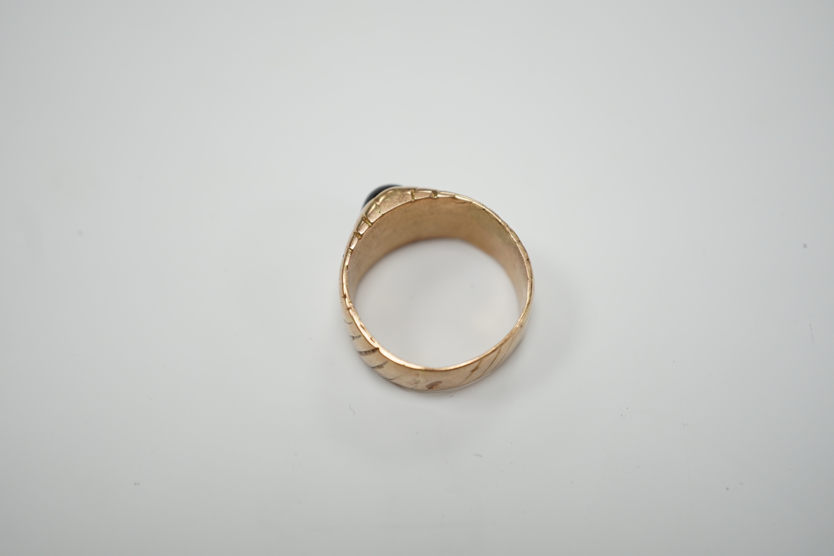 An antique engraved yellow metal and cabochon red paste set ring, size Q, gross weight 5.8 grams.